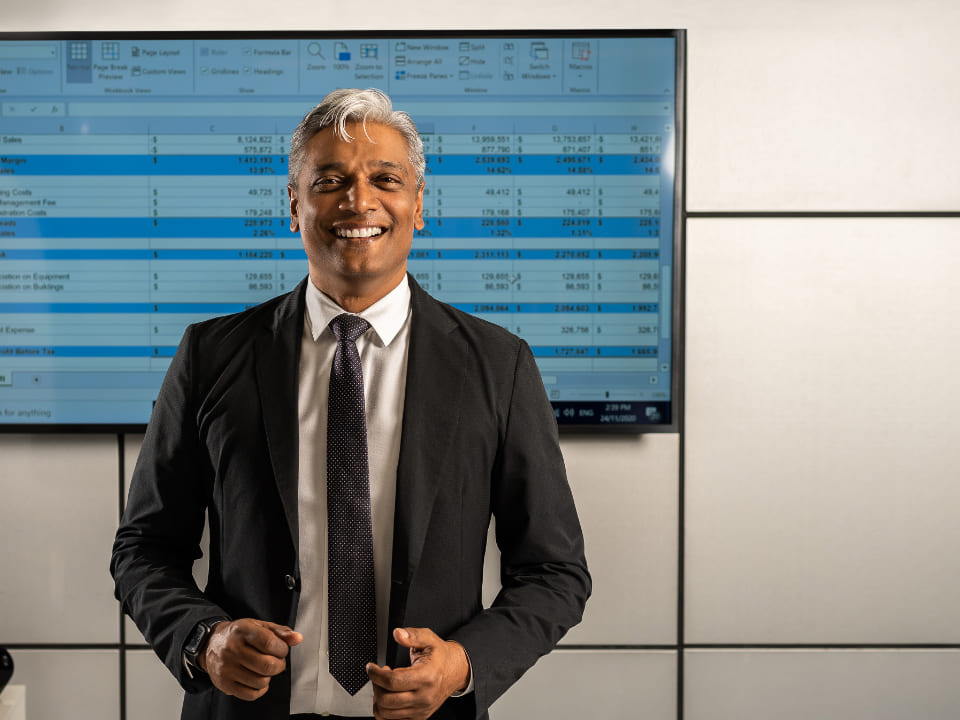 Greg Vales standing in front of stock TV